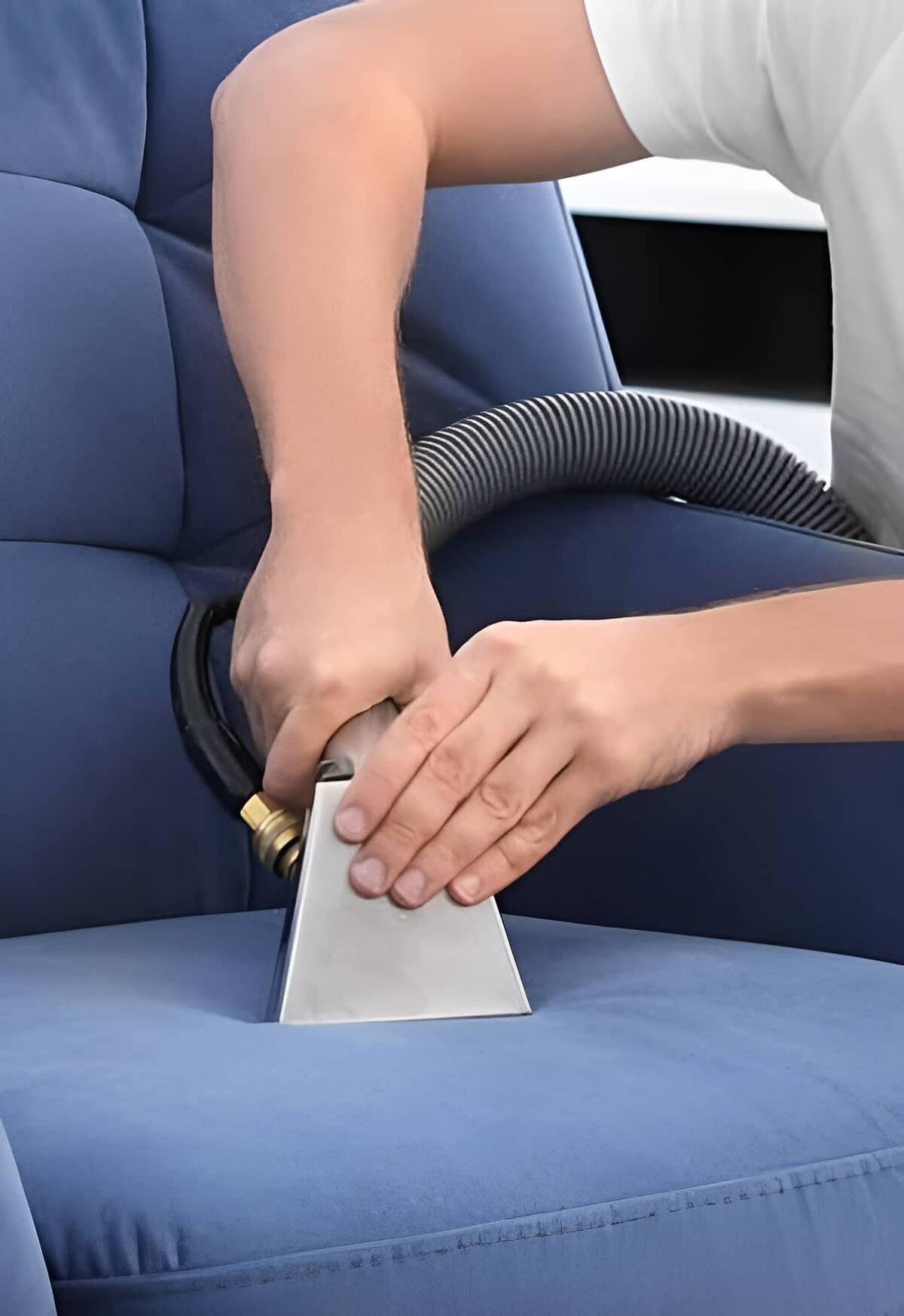 Upholstery cleaning tool lifting dirt from a blue fabric armchair